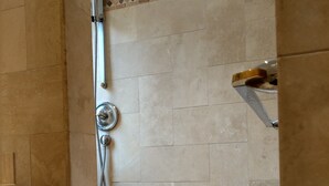 Un área de ducha con cabezal de ducha de mano y grifo instalado en la pared.