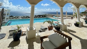 Un espacio exterior techado con piscina, asientos y vistas al océano.
