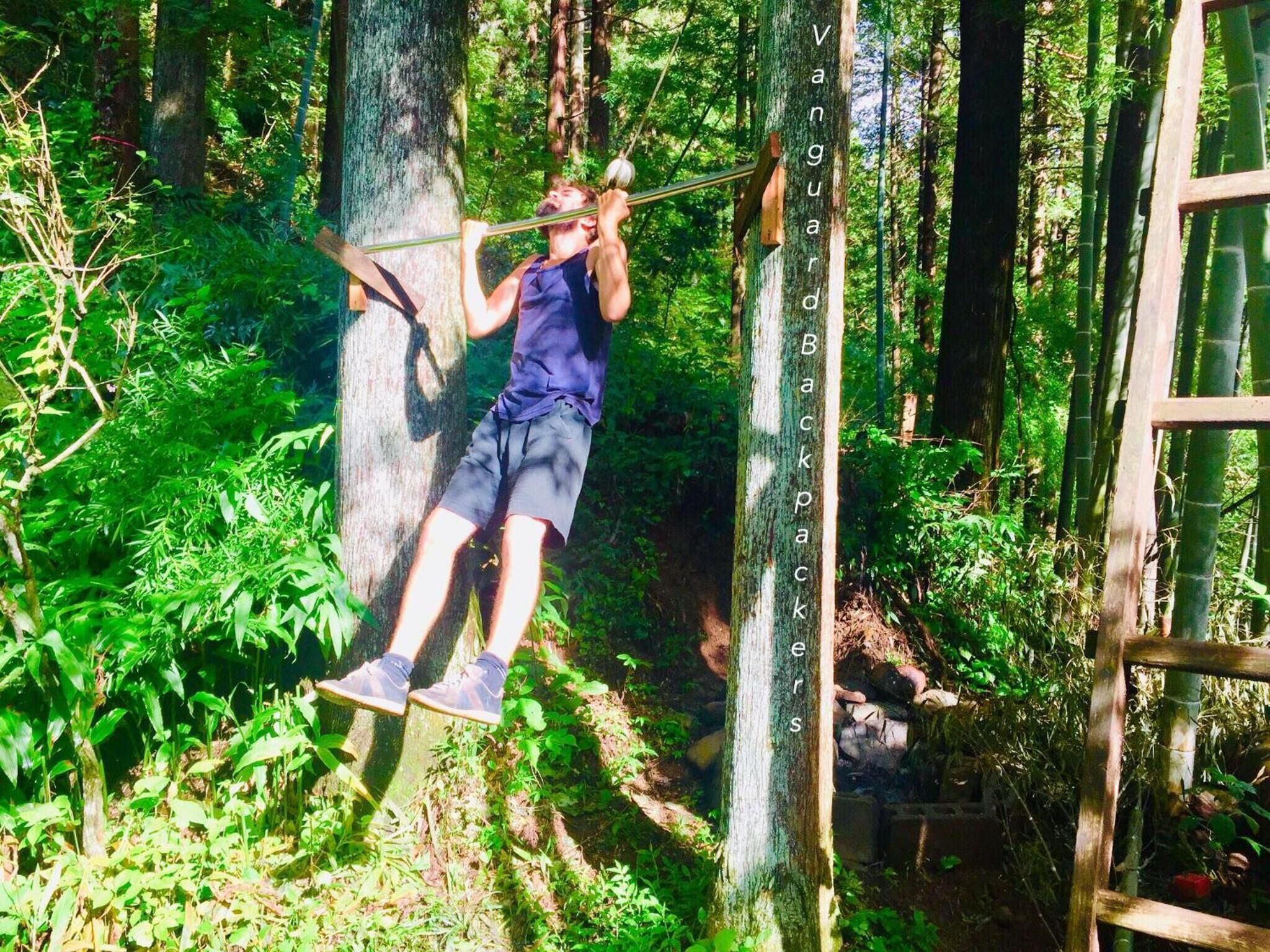 Una persona realiza una acrobacia de parkour sobre una estructura de madera en un área boscosa.