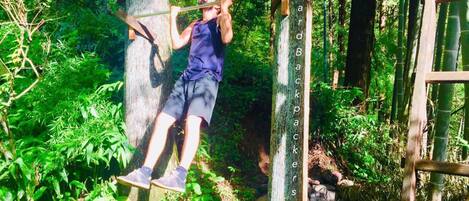 Una persona realiza una acrobacia de parkour sobre una estructura de madera en un área boscosa.