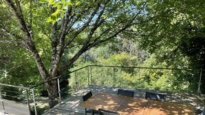 An outdoor deck with a wooden table and chairs, surrounded by trees. - Pretty character house with swimming pool in Entre deux Mers (min. 5 nights) (Romagne)