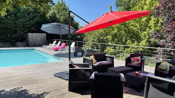A poolside area with lounge chairs, a red umbrella, and a wooden deck. - Pretty character house with swimming pool in Entre deux Mers (min. 5 nights) (Romagne)