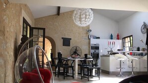 A compact living space with a dining area, kitchenette, and a hanging chair. - Pretty character house with swimming pool in Entre deux Mers (min. 5 nights) (Romagne)