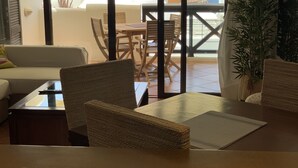 A room with a view of the sea, a dining area with wicker furniture, and a potted plant.