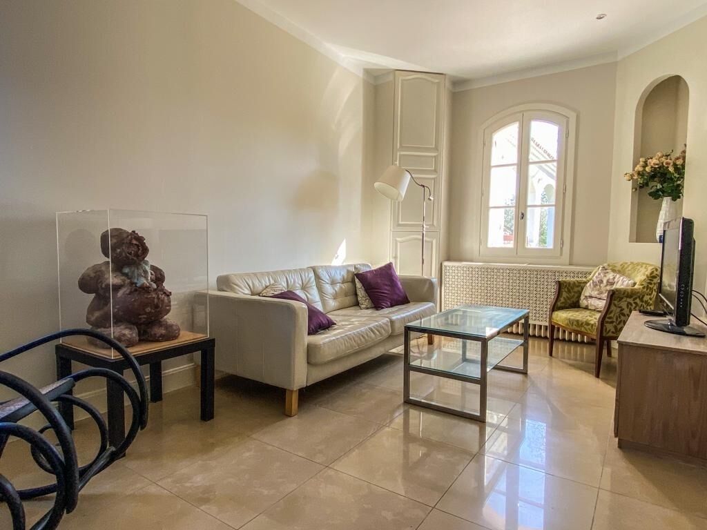 A living room with a sofa, a glass coffee table, a television, and a decorative sculpture.