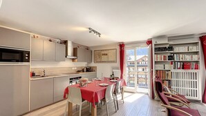 A modern kitchen with a dining area, a bookshelf, and a view of a mountain.