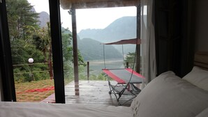 A room with a bed, a view of a mountain, and a balcony with a swing. - Moonlight Village Pension (Danyang)
