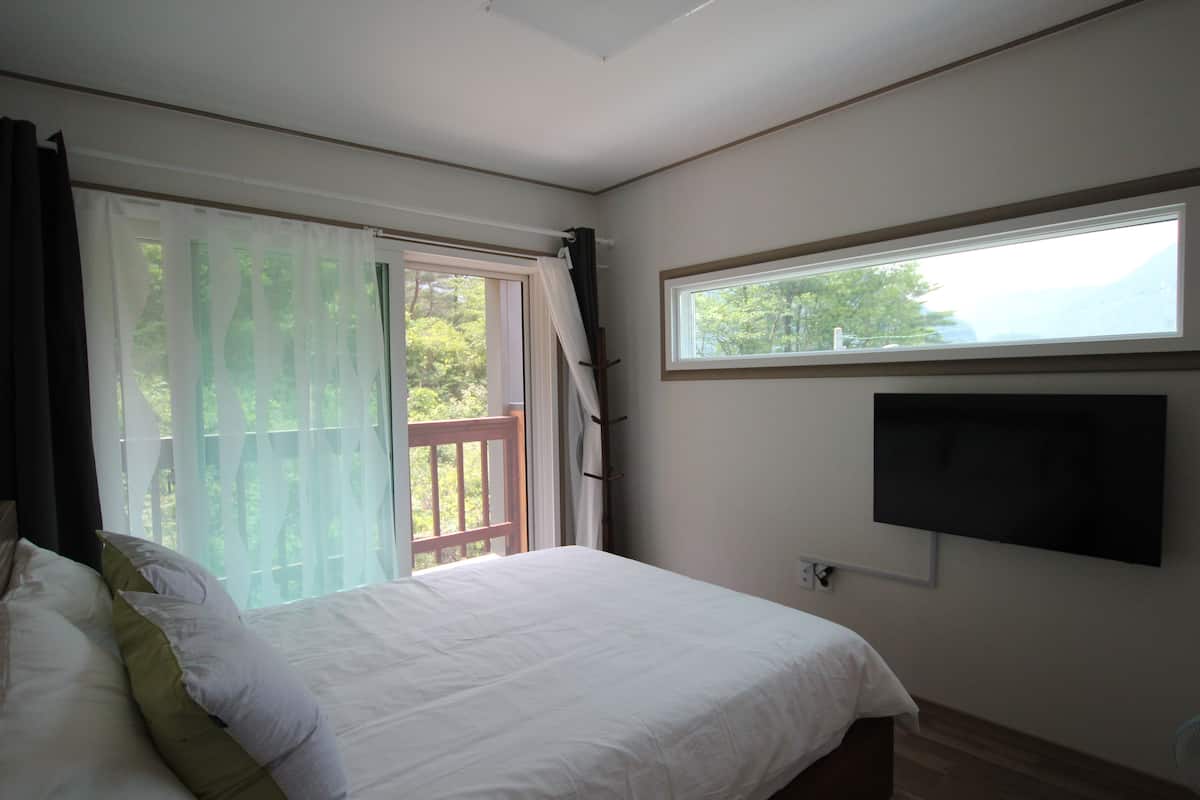 Une chambre à coucher avec un lit, une fenêtre et un téléviseur fixé au mur.
