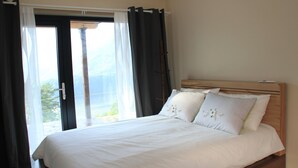 A bedroom with a bed, curtains, and a view of the outdoors. - Moonlight Village Pension (Danyang)