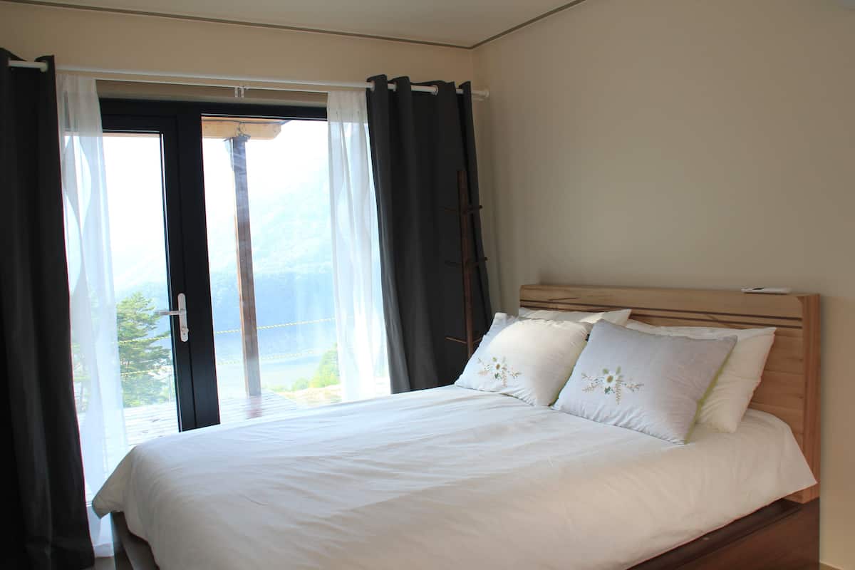 Une chambre à coucher avec un lit, des rideaux et une vue sur l’extérieur.
