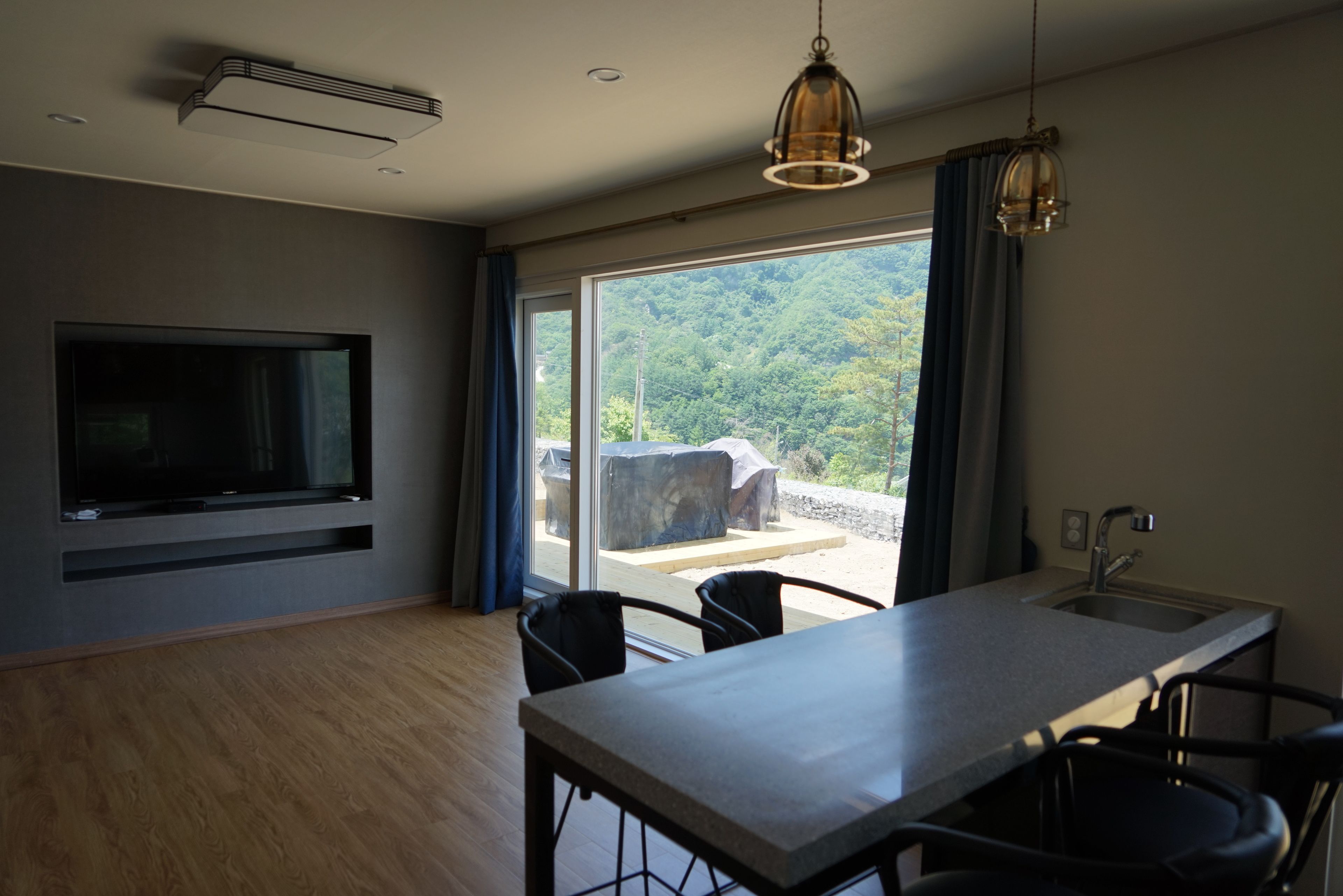 Una cocina moderna con un ventanal grande, un televisor empotrado y un comedor con sillas.