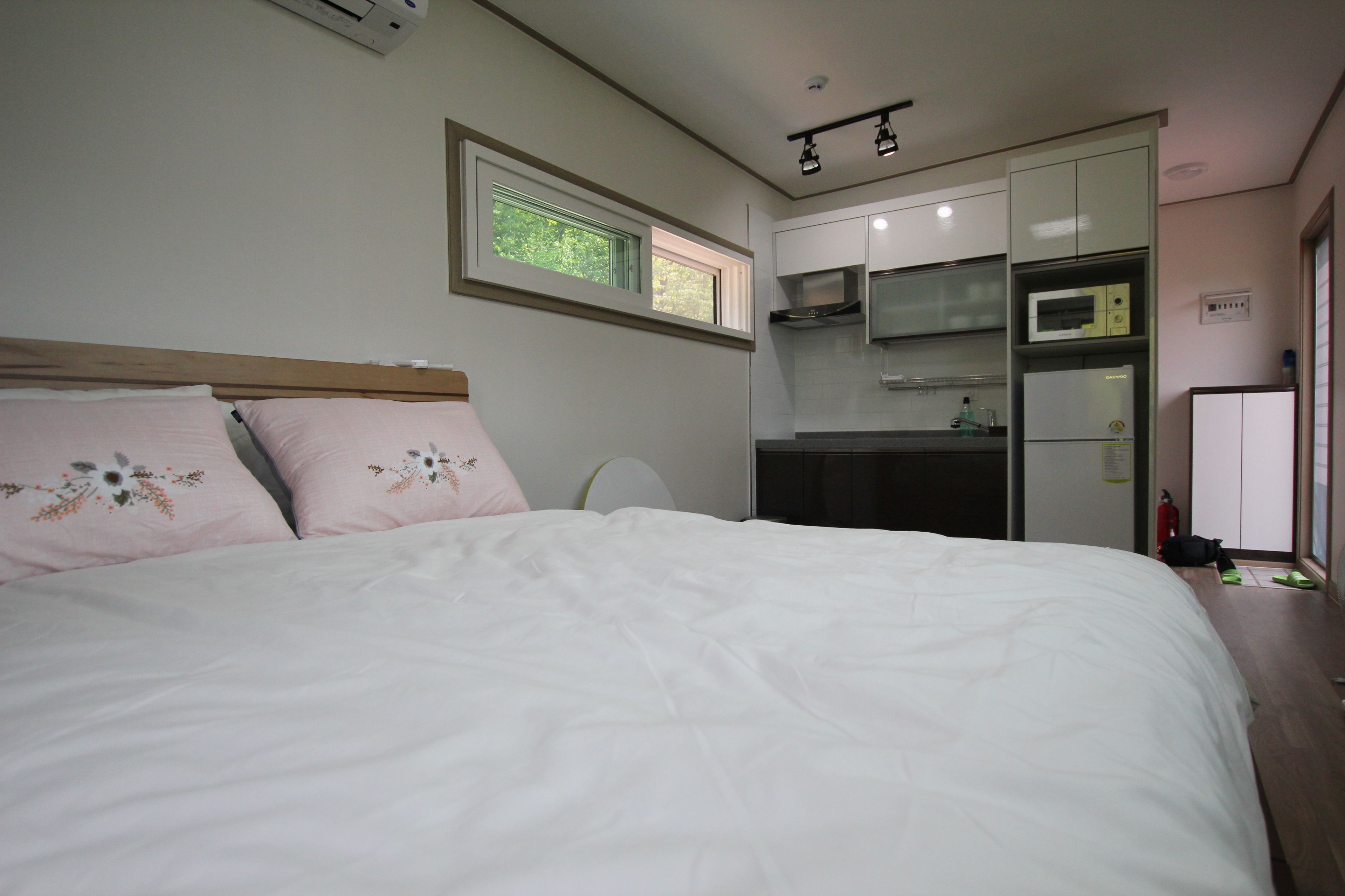 Un dormitorio con cama, ventana y kitchenette.