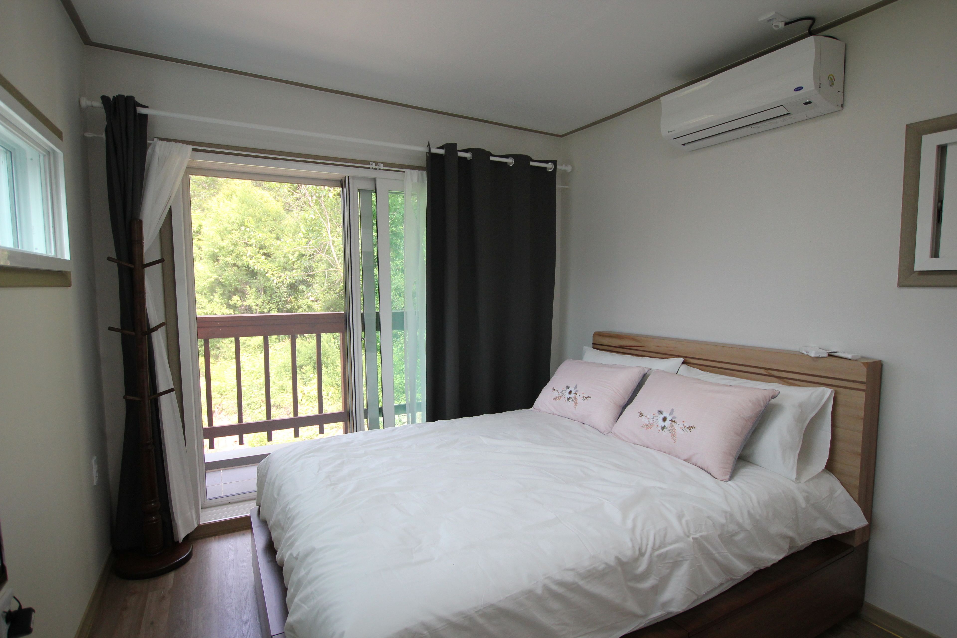 Un dormitorio con cama, ventana con cortinas y equipo de aire acondicionado.