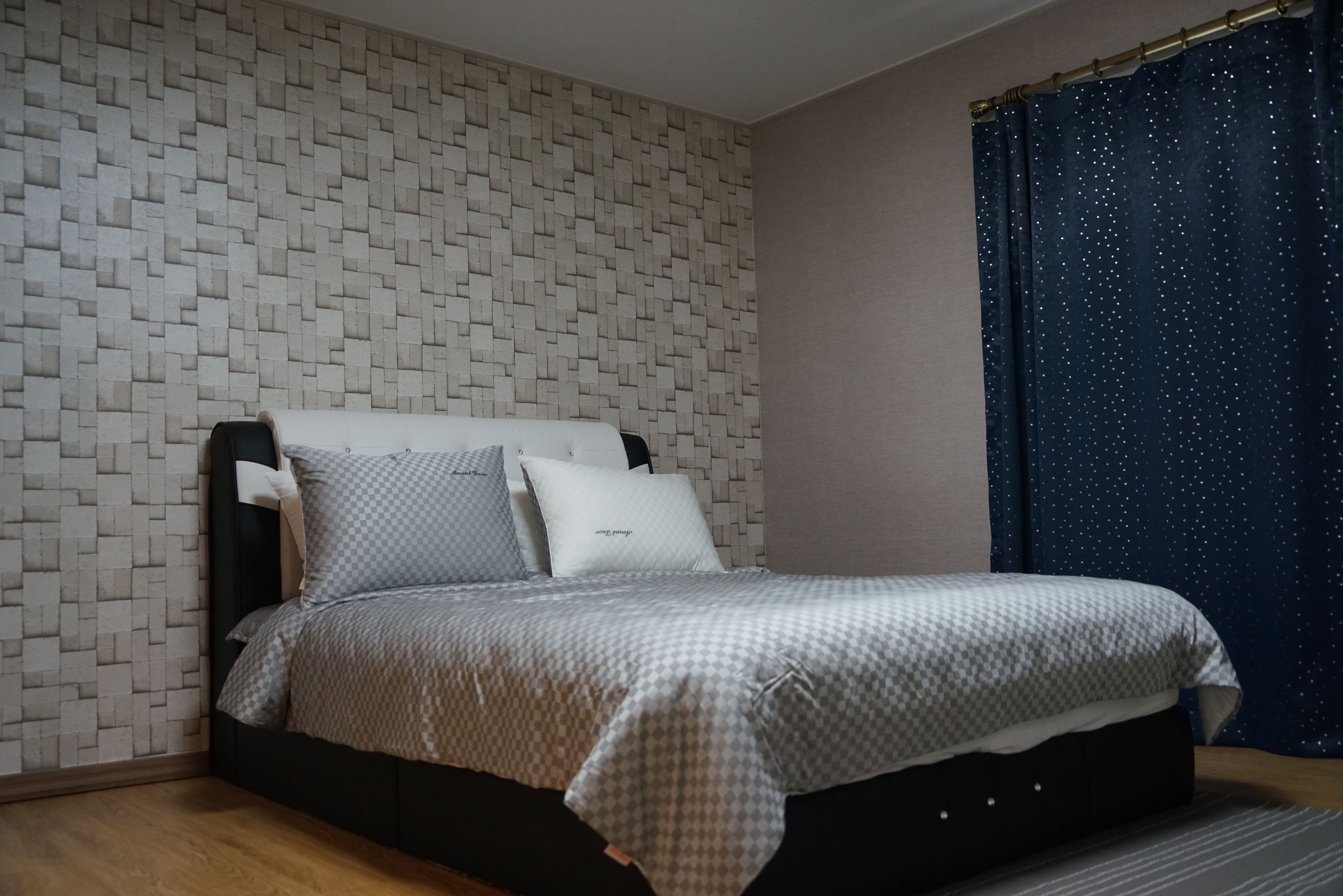 Un dormitorio con pared estampada, cama con colcha de cuadros y cortina con motivos de estrellas.