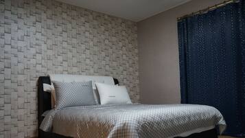 Un dormitorio con pared estampada, cama con colcha de cuadros y cortina con motivos de estrellas.