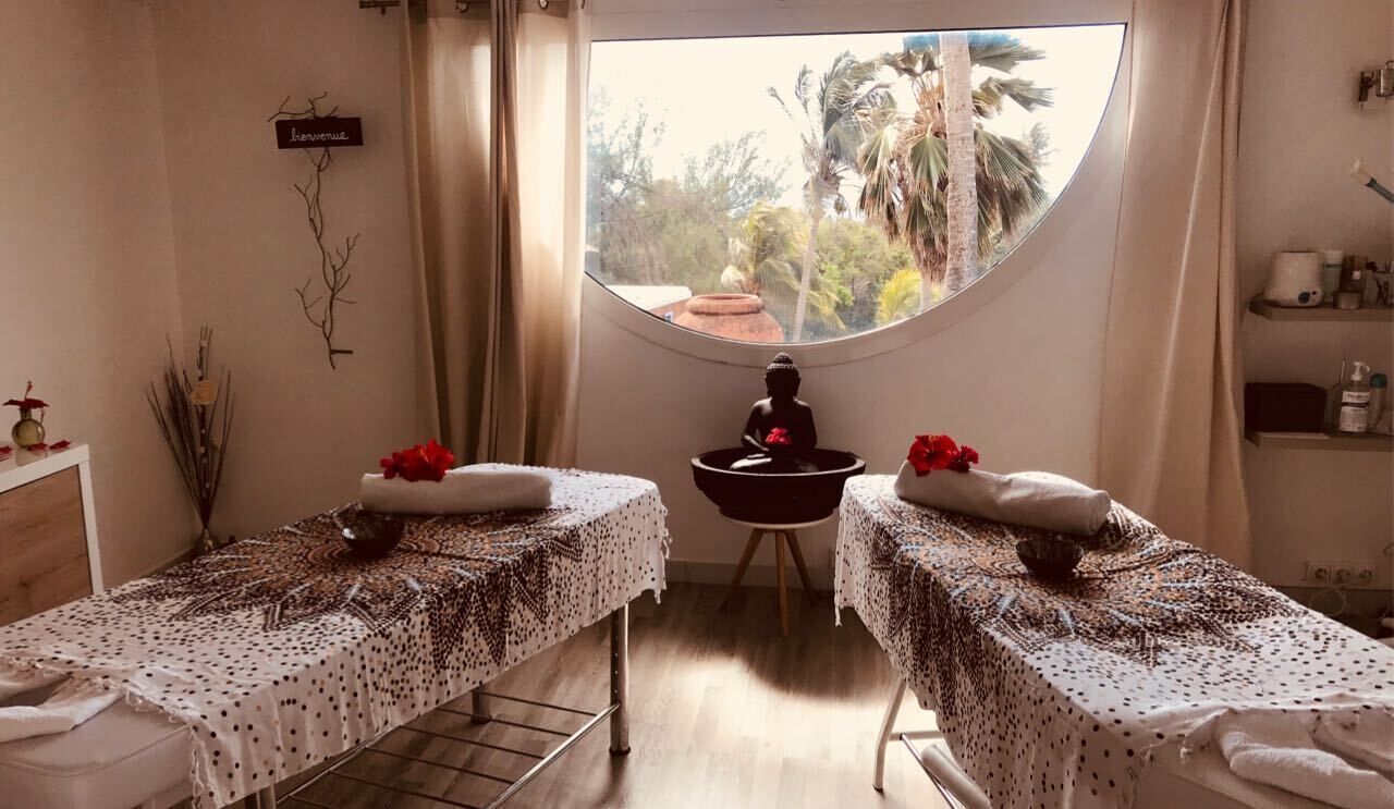 A room with two massage tables, each with a towel and a bowl, and a statue in the center.