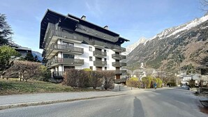 A multi-story building with balconies, surrounded by a mountainous landscape. - Cozy Apartment in Chamonix, 4 Pers, Near Brévent with Terrace and Parking (Chamonix-Mont-Blanc)