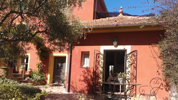 A courtyard with a red building, outdoor seating, and potted plants.