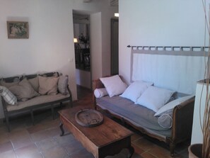 Uma sala com sofá, mesa de madeira e cama com dossel.