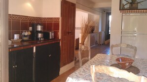 A kitchen with a coffee maker, toaster, and a dining table with chairs.