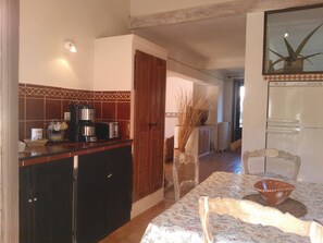 Cozinha com cafeteira, torradeira e mesa de jantar com cadeiras.