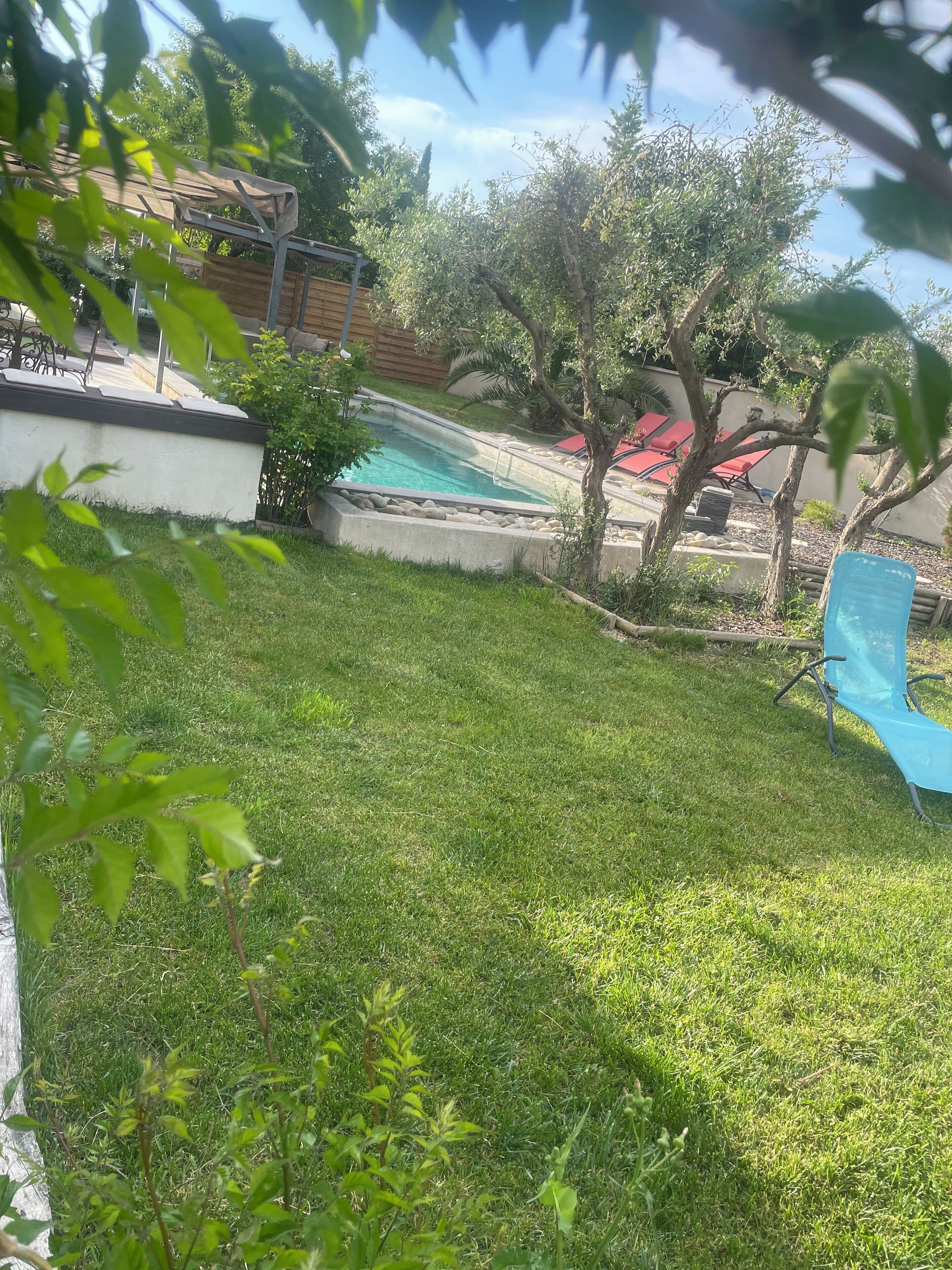 A backyard with a swimming pool, a covered patio, and a grassy lawn.