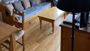 Une pièce chaleureuse avec un canapé en bois, une table en bois et une lampe.