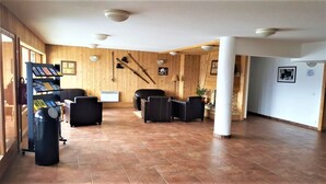 Un hall d’entrée spacieux avec des murs en bois, un comptoir d’accueil, des sièges en cuir noir et une poubelle.