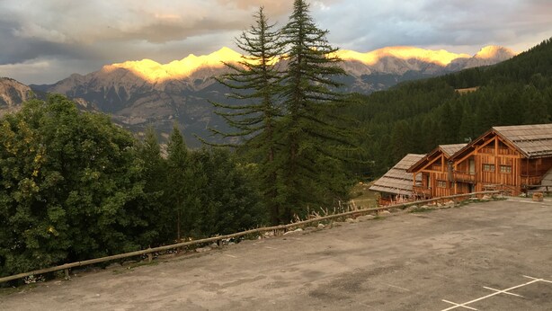 Un chalet de montagne doté d’un espace de stationnement et offrant une vue sur les montagnes.