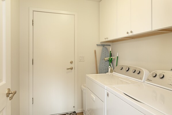 Una sala de lavandería con una puerta blanca, una lavadora y un tendedero.