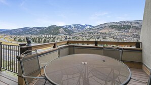 A balcony with a round metal table and chairs, overlooking a mountainous landscape with a clear sky. - 15 Chambertin Townhomes  3 Bedroom Townhouse by RedAwning (Avon)