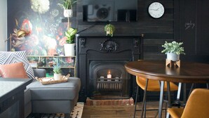 A cozy living room with a fireplace, a sofa, a coffee table, and a TV mounted on the wall.