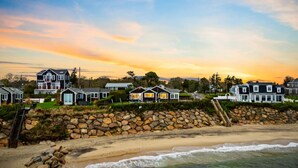 A beachfront property with multiple houses, a stone wall, and a staircase leading to the beach.