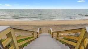 A wooden staircase leading to a beach with a clear view of the ocean.