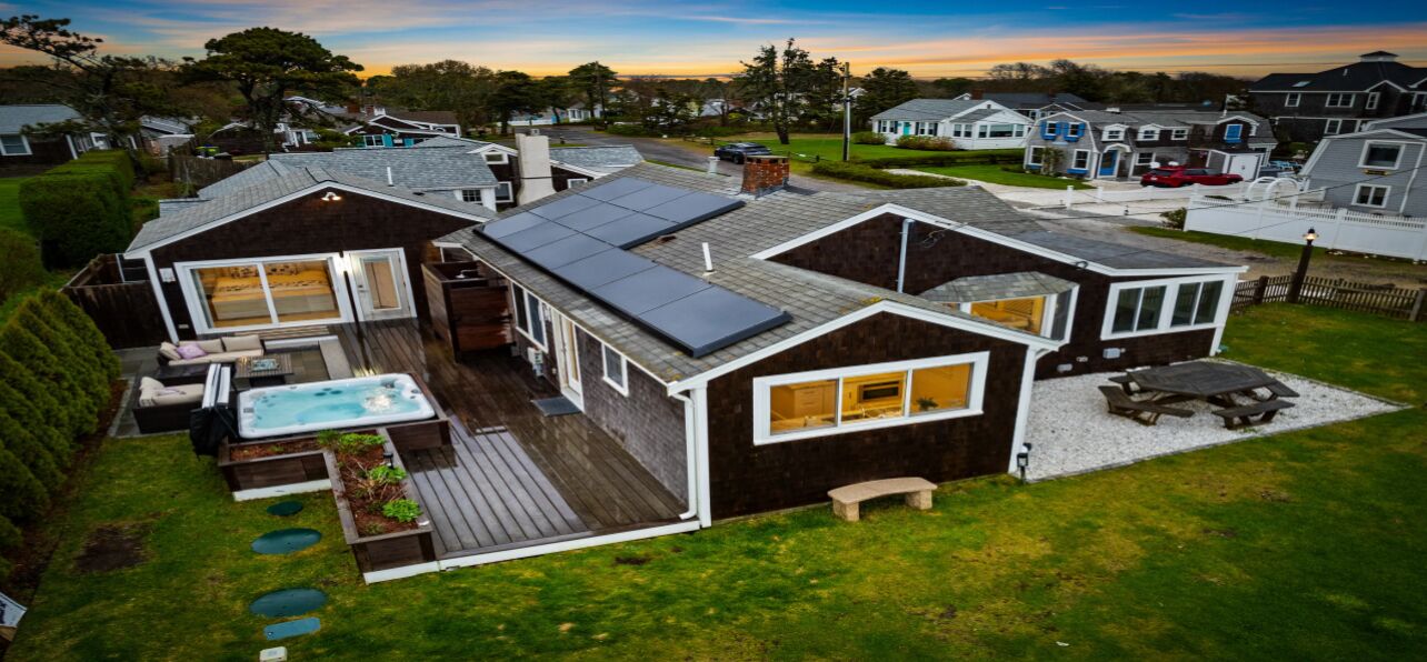 A modern house with a large deck, a hot tub, and a covered patio.
