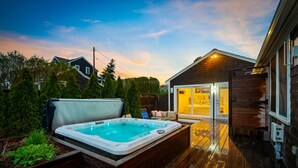 A hot tub on a wooden deck with a house in the background.