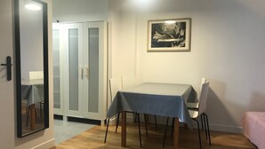 A room with a dining table, chairs, a bed, a wardrobe, and a framed picture on the wall. - Cheap Paris. New apartment in town house near the center.   (Seine-St-Denis)