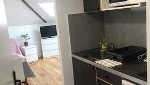 A modern kitchen with a microwave, sink, and a small refrigerator. There is a wooden floor and a white cabinet in the background. - Cheap Paris. New apartment in town house near the center.   (Seine-St-Denis)
