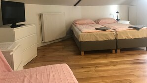 A bedroom with a skylight, a bed with pink bedding, a desk with a computer, and a radiator. - Cheap Paris. New apartment in town house near the center.   (Seine-St-Denis)