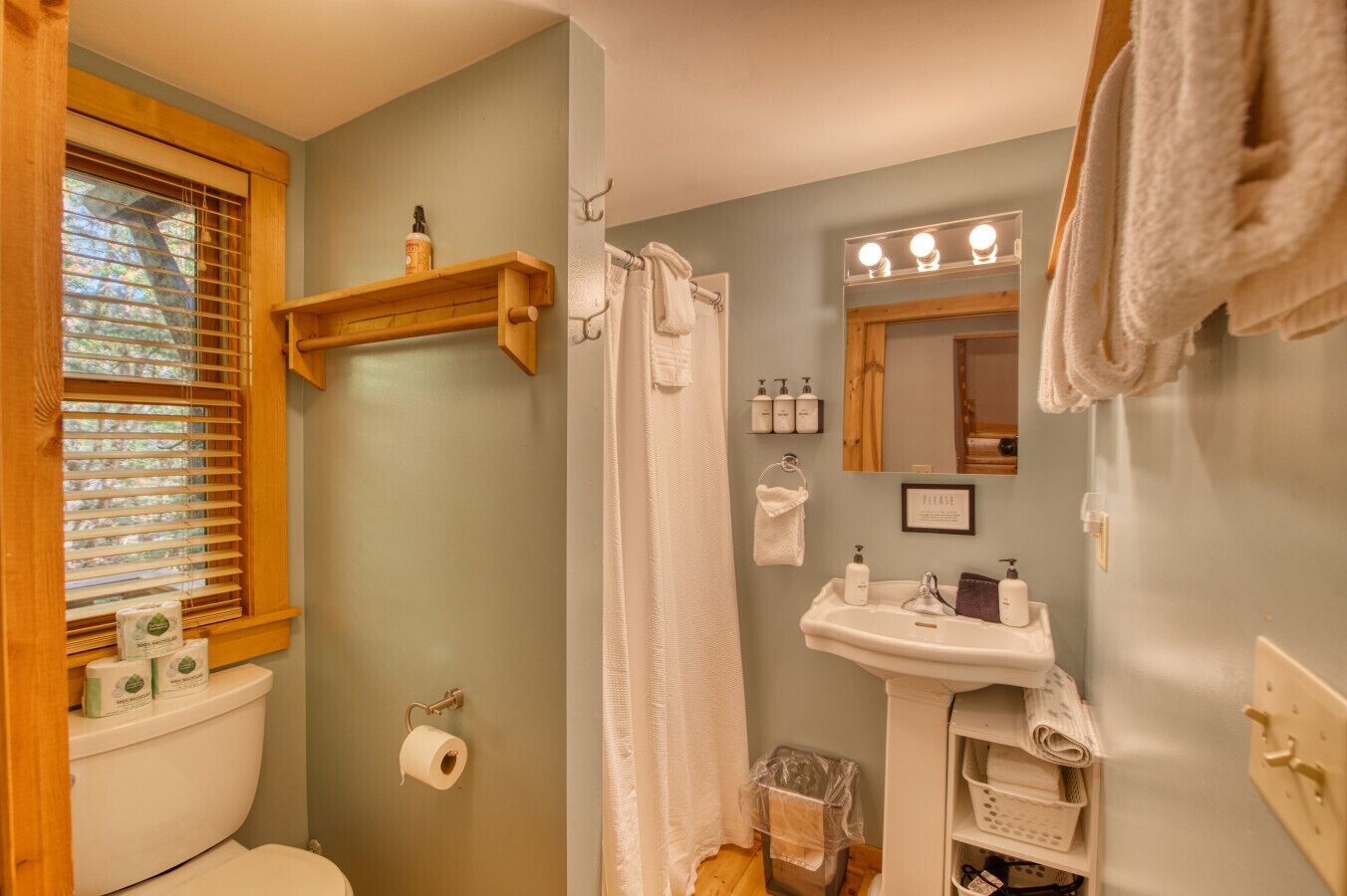 A bathroom with a toilet, shower, sink, and towel rack.