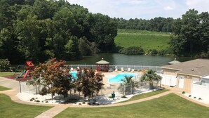 Ein umzäunter Außenbereich mit Schwimmbad, Spielplatz und Laube.