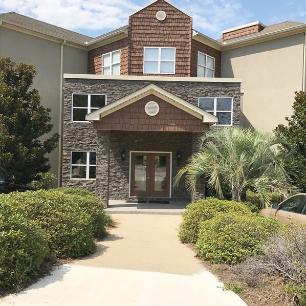 A multi-story building with a stone facade, a central entrance with a door, and a small porch area.
