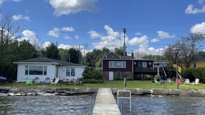 Un quartier résidentiel doté d’une jetée qui s’avance dans un plan d’eau, entouré de maisons et de verdure.