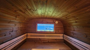 Une cabane en bois dotée d’une fenêtre donnant sur un plan d’eau et un pont.