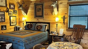 Ein gemütliches Blockhaus-Zimmer mit einem Bett, einem Esstisch und Stühlen.