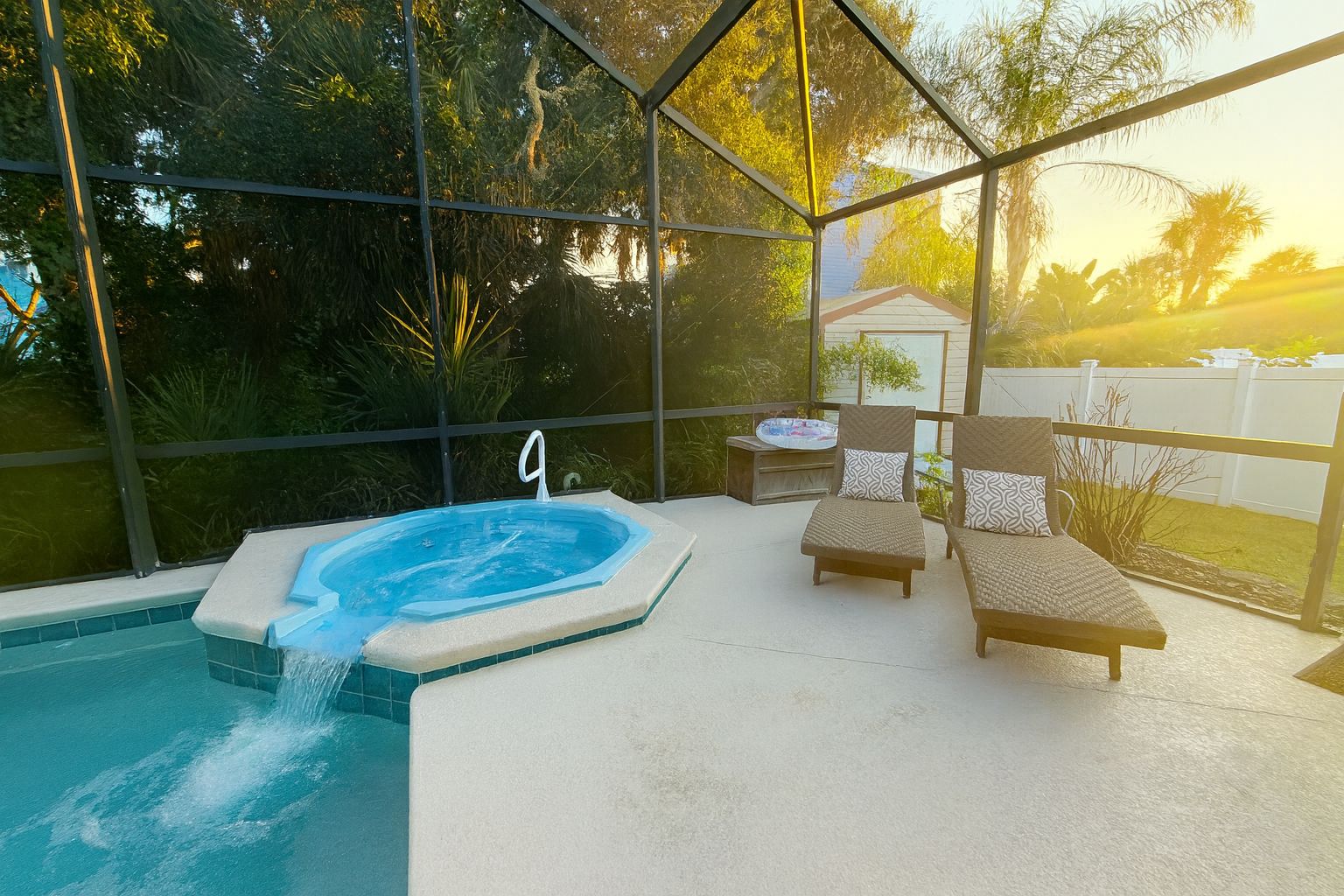 Un bain à remous avec un panneau portant le numéro 9, deux chaises longues et une vue sur les arbres et une maison, le tout visible à travers une paroi de verre.