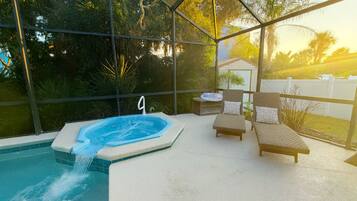 Un bain à remous avec un panneau portant le numéro 9, deux chaises longues et une vue sur les arbres et une maison, le tout visible à travers une paroi de verre.