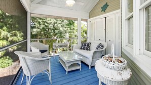 A covered porch with wicker furniture, a ceiling fan, and a view of greenery. - 3BR Captiva Village Retreat with Private Pool & Spa, Steps to the Beach (Captiva)