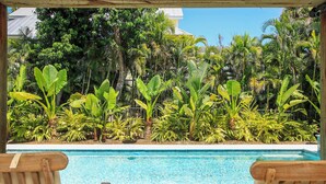 A pool with wooden chairs and lush tropical plants around it. - 3BR Captiva Village Retreat with Private Pool & Spa, Steps to the Beach (Captiva)