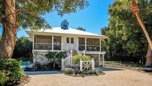 A two-story house with a covered porch and a small balcony. - 3BR Captiva Village Retreat with Private Pool & Spa, Steps to the Beach (Captiva)